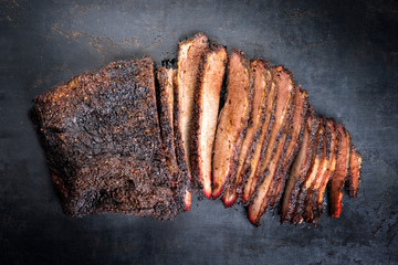 Traditional smoked barbecue wagyu beef brisket offered as top view on an old rustic board with copy...