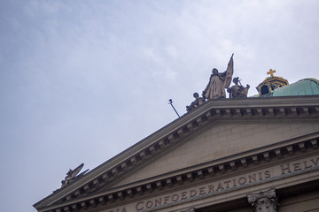 Fototapeta na wymiar Saint Statue on Roof Decoration of Bundeshaus in Bern, Switzerland, on Cloudy Sky Background