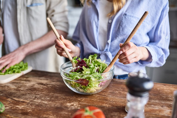 Couple preparing salad in kitchen
