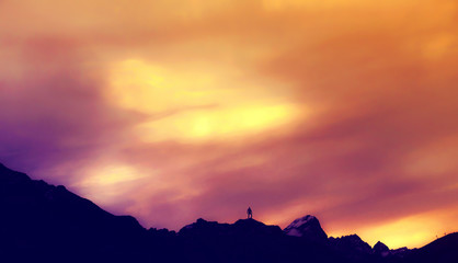Silhouette of Man Standing On Mountain Peak Under Pastel Sunset Skies Solitude Conquer Concept