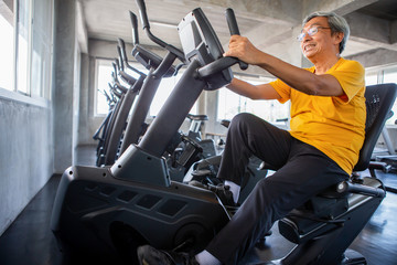 Senior older man exercising on cycling machine relaxing in fitness gym. aged . Old male workout .Mature sport training.rehabilitation.elderly Healthy lifestyle