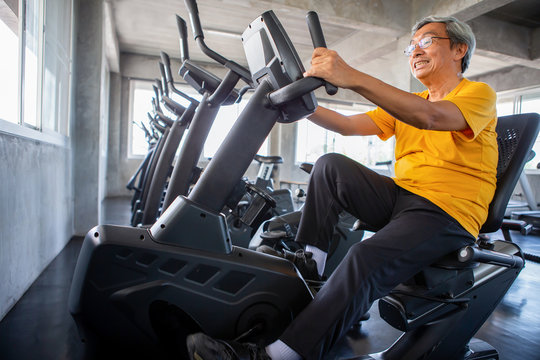 Senior Older Man Exercising On Cycling Machine Relaxing In Fitness Gym. Aged . Old Male Workout .Mature Sport Training.rehabilitation.elderly Healthy Lifestyle