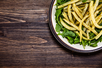Yellow beans with arugula on wooden background