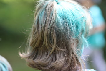 children on holiday painting each other with colours,  blue hair, yellow hair and hands on nature background