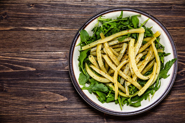 Yellow beans with arugula on wooden background