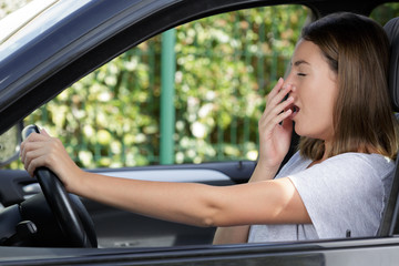 side view of a young woman yawning inside car