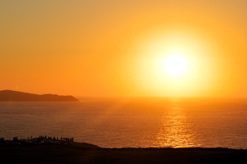 A group of people watching the sunset by the coast of the cantabrian sea, Cantabria, Spain