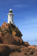 Fototapeta na wymiar old 19th century english lighthouse on top of a craggy rock