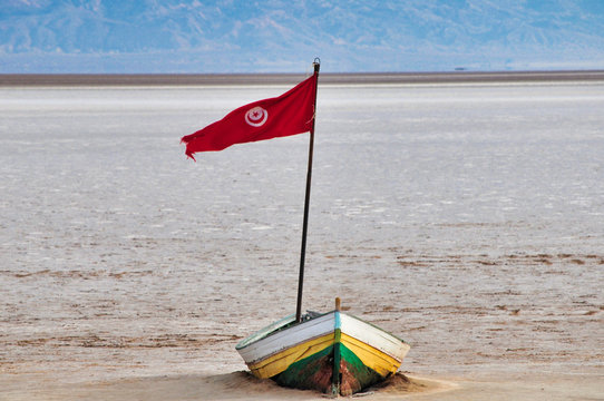 A small abandoned boat with red flag in the middle of Chott el Jerid salt lake in Tunisia