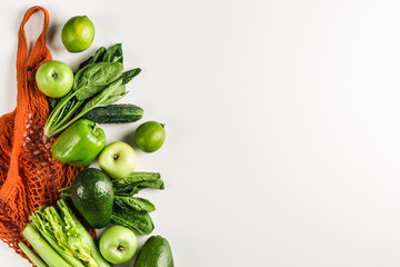 Green vegetables and fruits in orange string bag