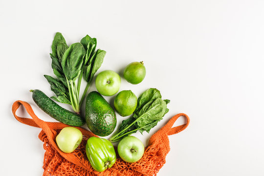 Green vegetables and fruits in orange string bag