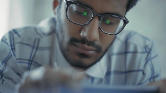 Close-Up, Indian Guy with Glasses Watching Music Video in Headphones on Smartphone