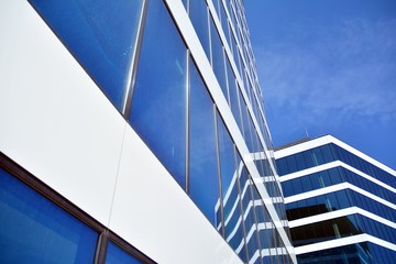 Fototapeta na wymiar New office building in business center. Wall made of steel and glass with blue sky. 