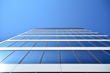 New office building in business center. Wall made of steel and glass with blue sky. 
