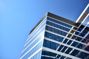 New office building in business center. Wall made of steel and glass with blue sky. 