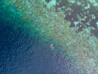 Aerial top down people snorkeling on coral reef tropical caribbean sea, turquoise blue water. Indonesia Wakatobi archipelago, marine national park, tourist diving travel destination