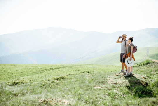 Couple enjoying beautiful landscape views, while traveling with backpacks in the mountains during the summer vacations. Image with copy space