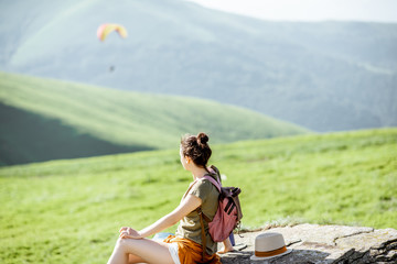 Woman enjoying landscape view on the mountains with paraglider flying on the background