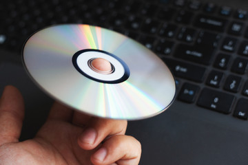 The driver CD compact disc is spinning on the index finger against the background of a computer