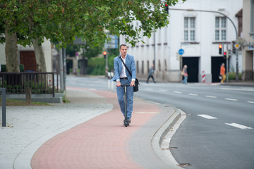 Mann fährt mit Elektroroller in der Stadt auf Radweg