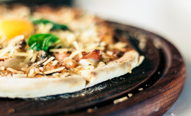 pizza with ham, mozzarella, tomato sauce from the oven on wooden plate in restaurant of Catania, Sicily, Italy.