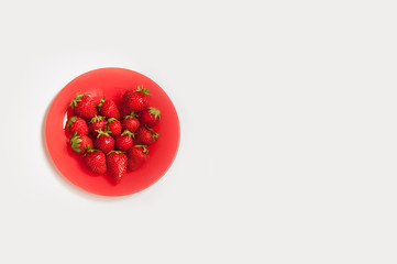 Red plate with fresh strawberries laid in heart shape