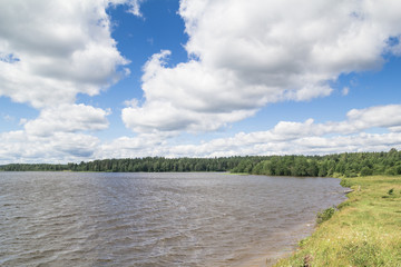 Sunny day on a calm lake in summer, with clouds on the sky