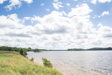 Sunny day on a calm lake in summer, with clouds on the sky
