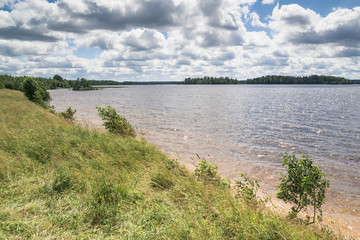 Sunny day on a calm lake in summer, with clouds on the sky