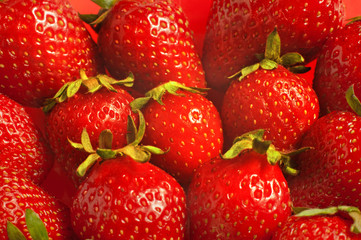 Heap of fresh strawberries on red background