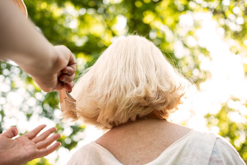 Woman doing an haircut to her grandmother outdoor