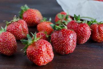 succulent juicy fresh ripe red strawberries on a dark wooden table