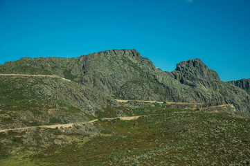Roadway passing through rocky landscape and green fields