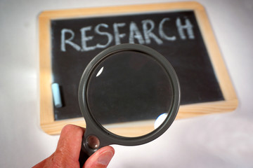 research message on chalkboard with magnifying glass