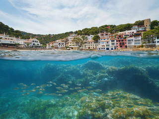 Fototapeta na wymiar Spain village on Mediterranean coast with fish underwater, Sa Tuna cove, Begur, Costa Brava, Catalonia, split view half over and under water