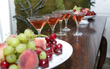  martini glasses of red wine cocktail on a wooden table of a fruit bar in a soft blurred background