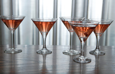 martini glasses of red wine cocktail on a wooden table of a bar on a silver background