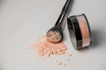 powder hill, black makeup brush, a jar of powder lying on the edge