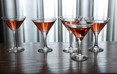 martini glasses of red wine cocktail on a wooden table of a bar on a silver background