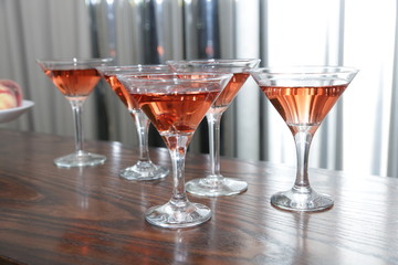 martini glasses of red wine cocktail on a wooden table of a bar on a silver background