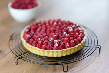 Raspberry tart with vanilla cream and icing sugar.