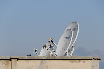 Satellite dish antenna for receiving a television signal on the roof of a building.