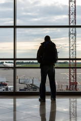 Silhouette of man with luggage on the background of a window at the airport, air transportation