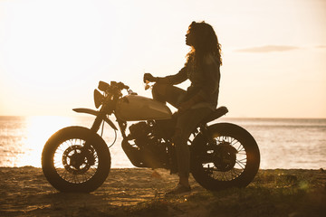 Fototapeta na wymiar Beautiful girl having fun driving her custom cafe racer motorcycle
