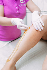 Removing unnecessary hair on the legs. sugaring in a beauty salon. Depilatory