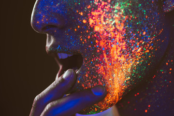 Handsome boy dancing at the rave party with fluorescent paintings on his face