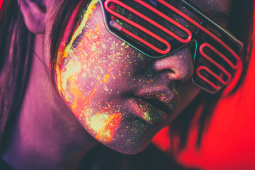 Mooie jonge vrouw dansen en feest maken met fluorescerende verf op haar gezicht. Neon gezichtsportretten