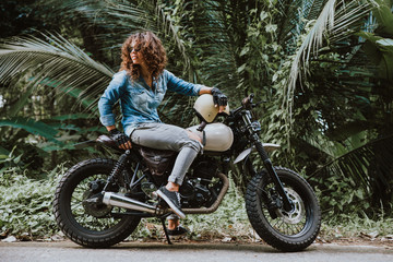 Beautiful girl having fun driving her custom cafe racer motorcycle