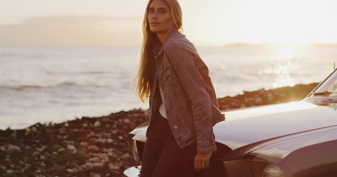 Beautiful woman sitting on the hood of a vintage car