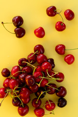 Obraz na płótnie Canvas Freshly picked cherries on a bright yellow background. Top view, high resolution